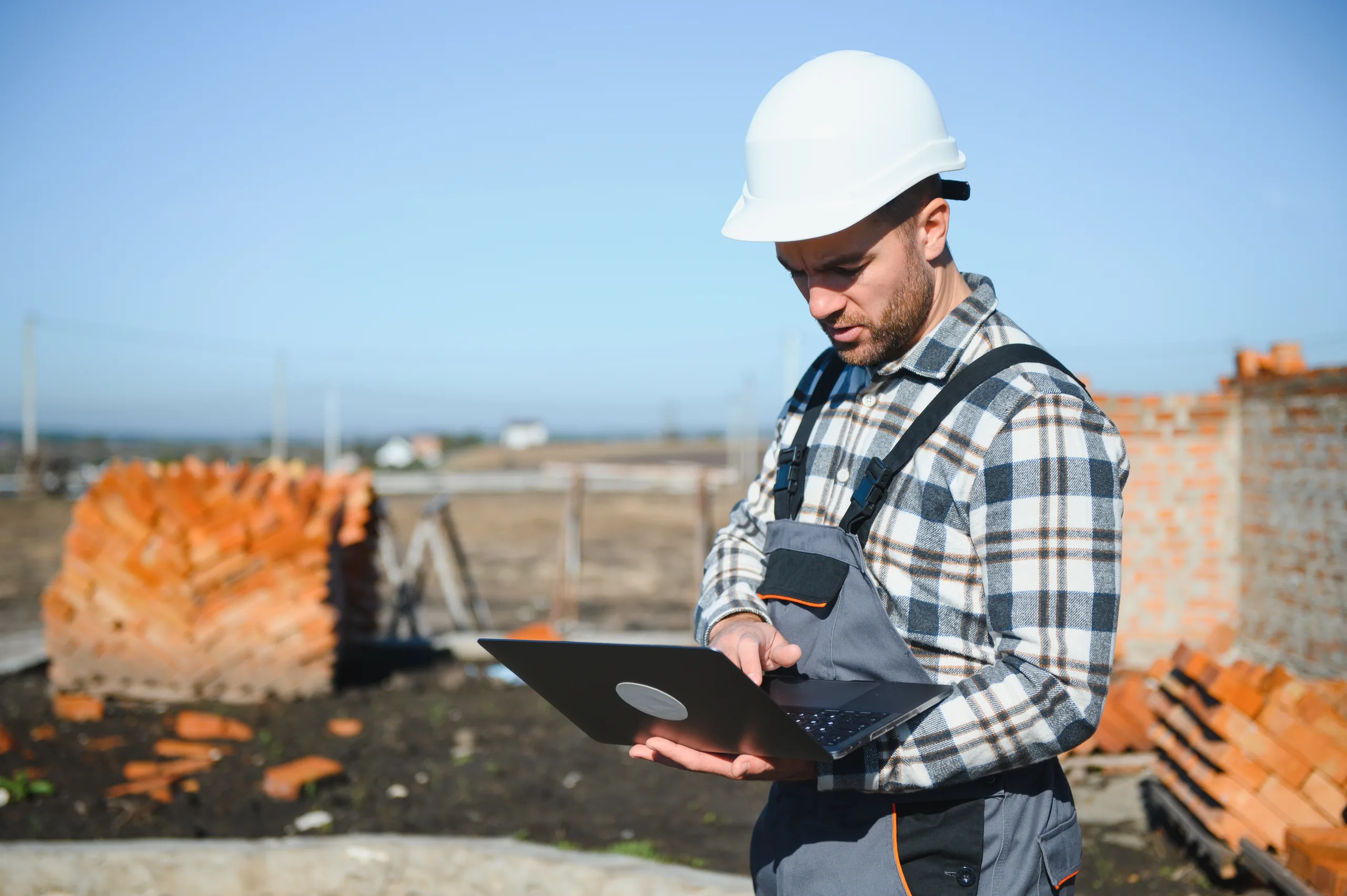 A construction business owner checking a laptop on a residential job site